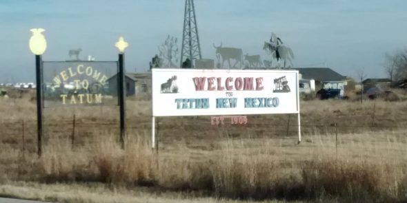 Welcome sign to New Mexico with an oil rig in the background.
